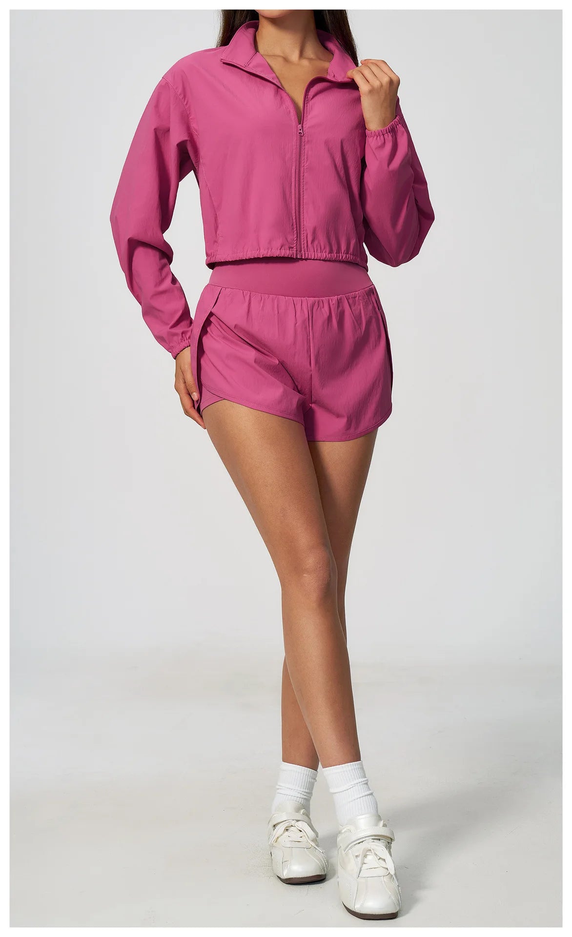 Pink zip-up athletic jacket with long sleeves and matching drawstring shorts, side view