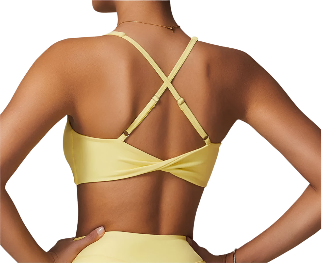 Back view of a stylish women's fitness two-piece set in yellow with crisscross straps
