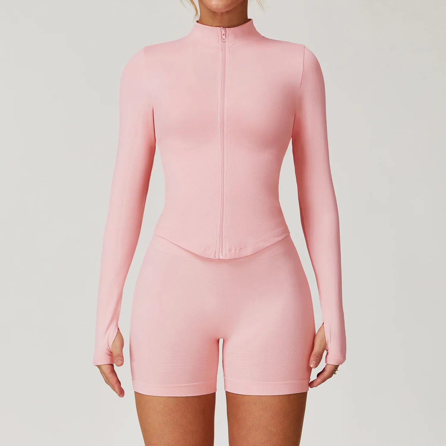 Xooie Fit women's zipper workout set in light pink long sleeve zip top with thumbholes and high waist shorts
