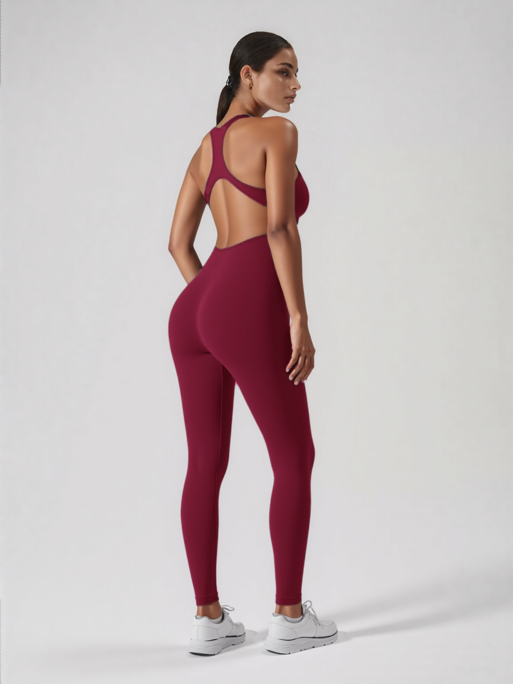 Xooie Fit backless workout jumpsuit in burgundy on model showing open racerback cutout and fitted leggings