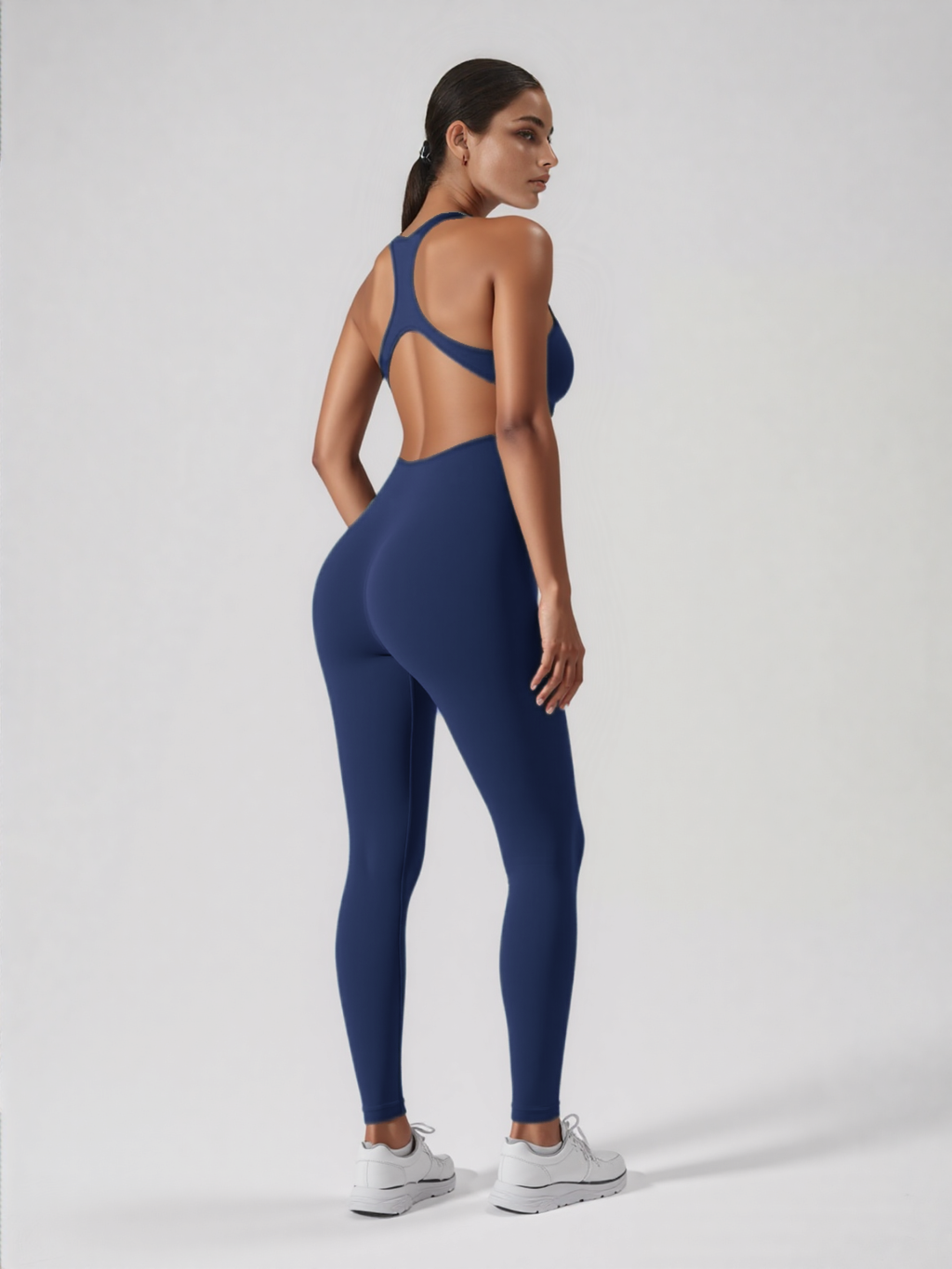 Xooie Fit navy blue backless workout jumpsuit modeled by woman with racerback cut open back and full length leggings