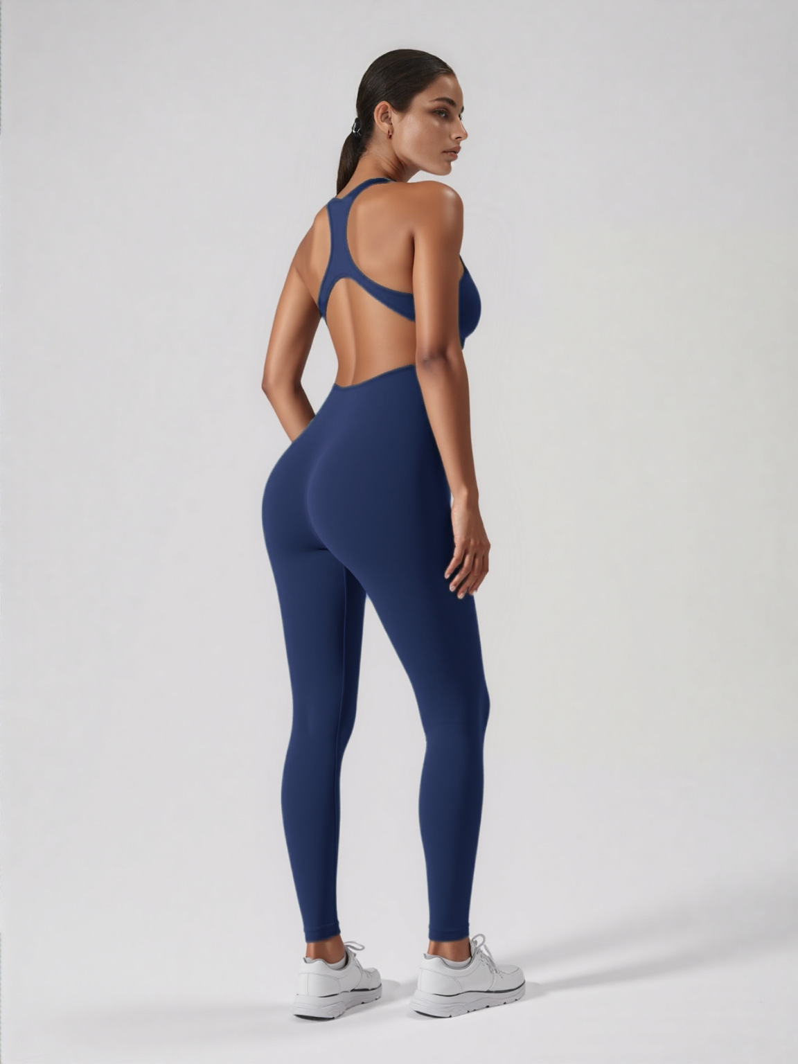 Xooie Fit navy blue backless workout jumpsuit modeled by woman with racerback cut open back and full length leggings
